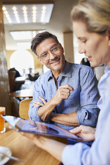 Lächelnder Mann und Frau mit Tablet in einem Cafe - PNEF01391