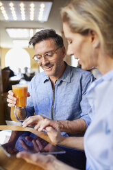 Lächelnde Frau und Mann mit Tablet in einem Café - PNEF01392
