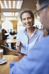 Smiling woman and man with tablet in a cafe - PNEF01394