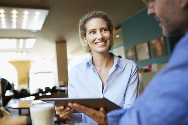 Smiling woman and man with tablet in a cafe - PNEF01395