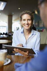 Smiling woman and man with tablet in a cafe - PNEF01396