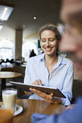 Lächelnde Frau und Mann mit Tablet in einem Cafe - PNEF01397