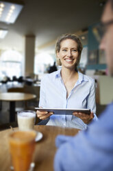 Smiling woman and man with tablet in a cafe - PNEF01398