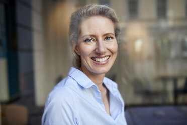 Portrait of smiling woman behind windowpane - PNEF01404