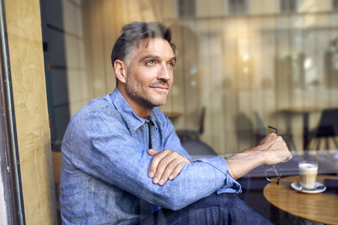 Porträt eines Mannes hinter einer Fensterscheibe in einem Cafe - PNEF01408