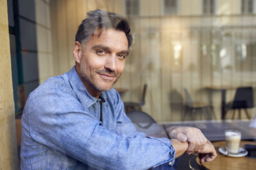 Portrait of confident man behind windowpane in a cafe - PNEF01409