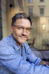 Porträt eines selbstbewussten Mannes mit Brille hinter einer Fensterscheibe - PNEF01411