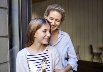 Portrait of happy mother with daughter at open door - PNEF01414