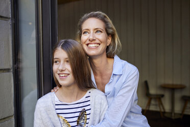Porträt einer glücklichen Mutter mit Tochter bei offener Tür - PNEF01416