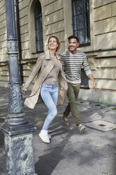 Glückliches Paar beim Spaziergang auf dem Bürgersteig in der Stadt - PNEF01421