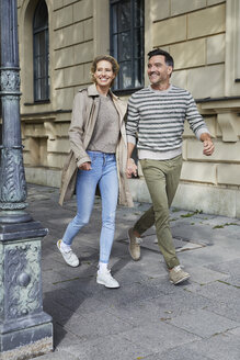 Glückliches Paar beim Spaziergang auf dem Bürgersteig in der Stadt - PNEF01422