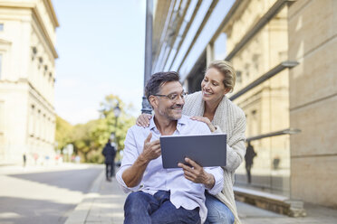 Happy couple using tablet in the city - PNEF01448