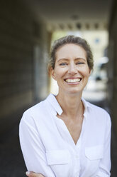 Portrait of happy woman wearing white shirt in the city - PNEF01452