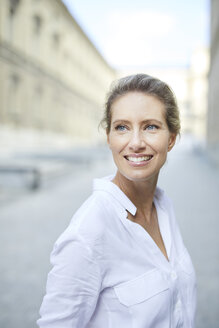 Porträt einer lächelnden Frau mit weißem Hemd in der Stadt - PNEF01453
