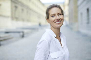 Portrait of smiling woman wearing white shirt in the city - PNEF01454