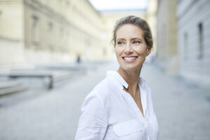 Porträt einer lächelnden Frau mit weißem Hemd in der Stadt - PNEF01455