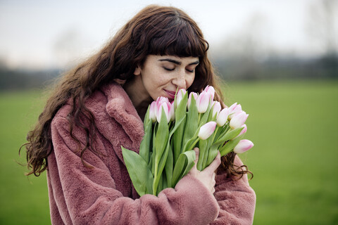 Young woman with bouquet of tulips and pink coat stock photo