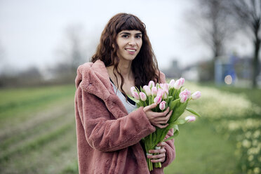Junge Frau mit Tulpenstrauß und rosa Mantel - FLLF00081