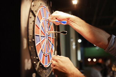 Nahaufnahme eines Mannes, der Darts aus einer elektronischen Dartscheibe nimmt - ZEDF02021