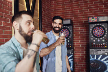 Zwei glückliche Freunde trinken Bier an der Dartscheibe in einer Kneipe - ZEDF02030