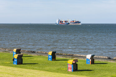 Deutschland, Cuxhaven, riesige Frachtschiffe passieren den Strand mit Strandkörben - RUNF01615