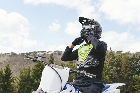 Motocross-Fahrer beim Aufsetzen des Helms - FBAF00315