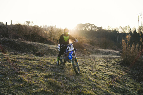 Motocross-Fahrer auf der Rennstrecke bei Sonnenuntergang, lizenzfreies Stockfoto