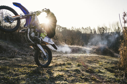 Motocross-Fahrer, der auf der Rennstrecke einen Wheelie macht - FBAF00342