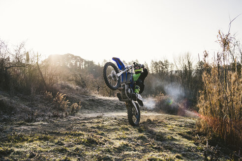 Motocross-Fahrer, der auf der Rennstrecke einen Wheelie macht - FBAF00343