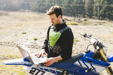 Porträt eines Motocross-Fahrers mit Laptop - FBAF00351