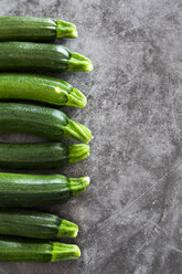 Zucchini in einer Reihe, grauer Hintergrund - GIOF05858