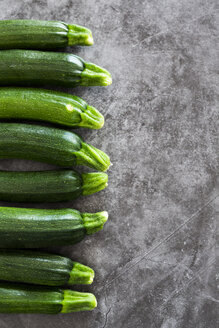 Zucchini in einer Reihe, grauer Hintergrund - GIOF05858