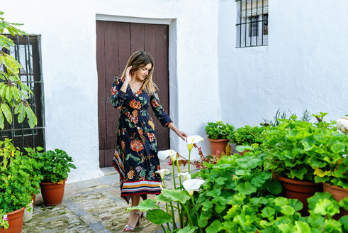 Spanien, Cadiz, Vejer de la Frontera, modische Frau betrachtet Callas im Innenhof - KIJF02454