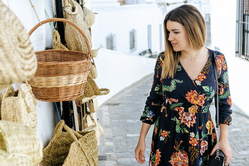 Spanien, Cadiz, Vejer de la Frontera, modische Frau betrachtet Taschen und Körbe in einem Geschäft - KIJF02458