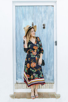 Spain, Cadiz, Vejer de la Frontera, fashionable woman standing in front of light blue wooden door - KIJF02459