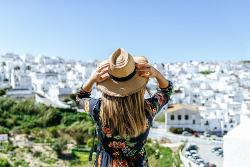 Spain, Cadiz, Vejer de la Frontera, back view of woman wearing straw hat looking at view - KIJF02464