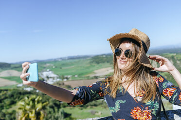 Spanien, Cadiz, Vejer de la Frontera, Porträt einer lächelnden Frau, die ein Selfie mit ihrem Smartphone macht - KIJF02473
