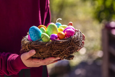 Girl holding Easter nest with colorful Easter eggs - SARF04196