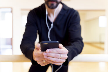 Nahaufnahme einer Balletttänzerin, die ein Mobiltelefon im Ballettstudio benutzt - FMOF00461