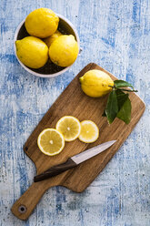 Zitronenscheiben, Küchenmesser und ganze Zitrone auf Holzbrett - GIOF05889