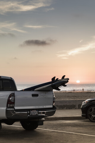 Surfbretter auf der Ladefläche eines am Strand geparkten Lastwagens bei Sonnenuntergang, Newport Beach, Kalifornien, USA, lizenzfreies Stockfoto