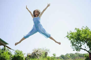 Portrait playful, carefree girl jumping for joy in back yard - FSIF03801