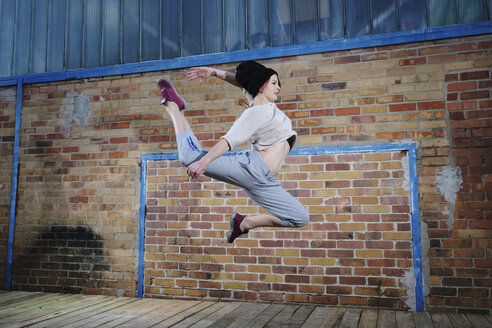 Weibliche moderne Tänzerin, die gegen eine Backsteinmauer tanzt - FSIF03817