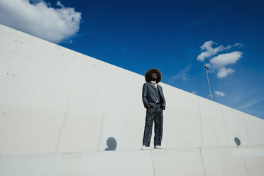 Portrait confident, cool, well-dressed young man with afro standing on urban wall - FSIF03890