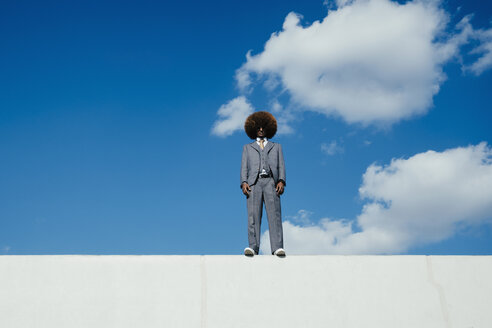 Porträt selbstbewusster, cooler, gut gekleideter junger Mann mit Afro an der Wand stehend gegen den Himmel - FSIF03893