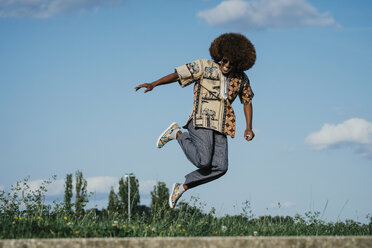 Carefree young man with afro jumping for joy - FSIF03897