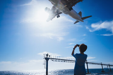 Junge mit Fotohandy fotografiert Flugzeug im Tiefflug in der Nähe des Flughafens von Lanzarote - FSIF03910