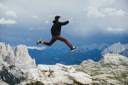 Unbekümmerter Junge springt über Felsen am Berg, Naturpark Drei Zinnen, Südtirol, Italien - FSIF03930