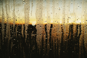 Raindrops and condensation on window with scenic sunset view - FSIF03932