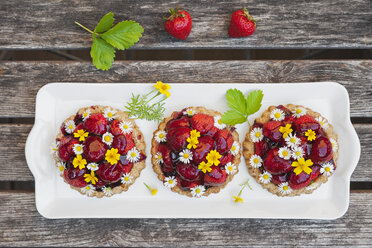 Hausgemachte Erdbeerherztörtchen mit Gänseblümchen und goldener Ringelblume, essbare Blüten, dunkles Holz - GWF06024